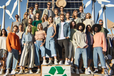 Photo d'un groupe de personnes diverses portant des vêtements éco-responsables, posant ensemble sur un podium fait de matériaux recyclés. En arrière-p